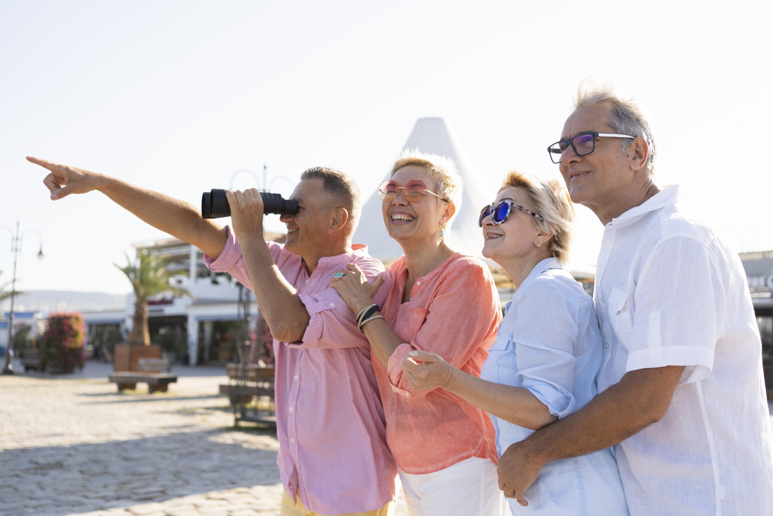 Four adults enjoying a sunny day at the beach, taking a selfie together.
