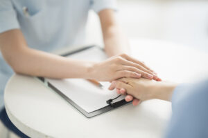 Nurse comforting patient holding hands over clipboard